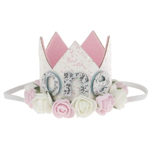 Close-up of white glitter crown with pink roses and silver one text for baby birthday