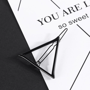 Detail of matte black geometric triangle hair clip with wavy metallic grip texture