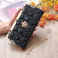 Detail of a black embroidered long wallet with golden corner guards and a crown emblem