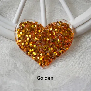 Detailed close-up of golden glitter heart-shaped resin accessory with hexagonal sequins