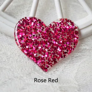 Macro view of a rose red glitter heart resin accessory on white lace fabric background