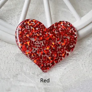 Macro shot of heart-shaped red resin charms with sparkling hexagonal glitter for DIY crafts