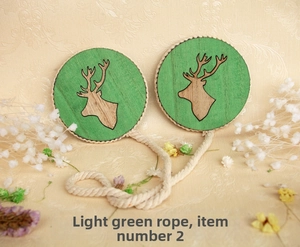 Detail view of rustic wooden curtain tieback with green deer motif and braided rope