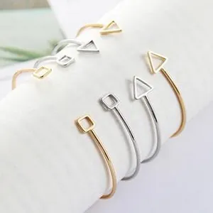 Macro view of adjustable minimalist open bangles with hollow geometric shapes in gold and silver
