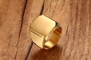 Macro shot of gold-plated stainless steel square signet ring on dark wood background