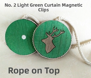 Close-up of light green wooden magnetic curtain tiebacks with a deer head engraving