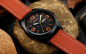Detalle del reloj militar impermeable con números naranjas y correa de cuero