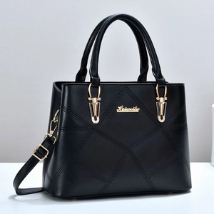 Detail of black quilted leather handbag showing golden logo and stitching texture