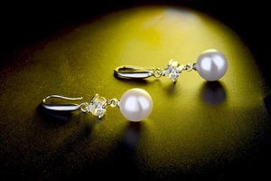 Macro shot of high-quality round white pearl earring with sparkling cubic zirconia accent