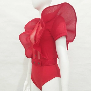 Detail view of the red mesh jumpsuit featuring exaggerated ruffles and single-breasted design