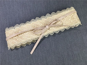 Nahaufnahme von breitem Spitzen-Korsettgürtel mit Blumenmuster und Schleife in Cremefarbe