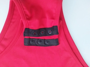 Close-up of red bodysuit with black snap button closure on the elastic fabric crotch