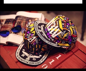 Détail de chapeaux hip hop avec motifs géométriques colorés et broderie de citation