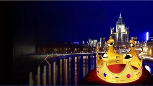 Detail of a gold king crown with red and blue gemstones and a plush red cushion lining