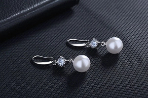 Macro detail of high-quality pearl earrings with sparkling round cubic zirconia accents