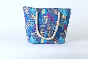 Close-up of blue canvas tote bag featuring vibrant tropical leaf patterns and rope handles