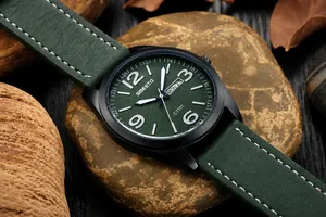 Primer plano de reloj deportivo militar con esfera verde y correa de cuero sobre piedras