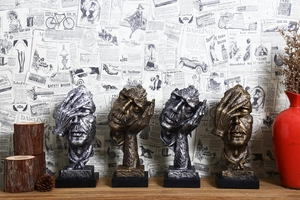 Artistic silent resin face sculptures in bronze and silver finishes on a vintage background