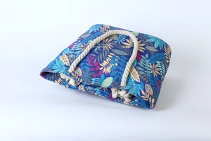 Detail of blue canvas tote bag featuring colorful leaf patterns and sturdy beige rope handles