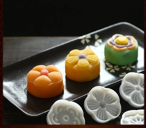 Set dettagliato di stampi bianchi tondi per mooncake su un piatto con pasticcini colorati