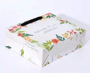 Elegant white paper gift bag with colorful floral prints and black handles for Valentine's