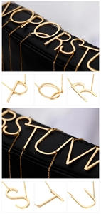 Detail of gold letter pendants O to V on black leather with fine square links