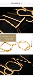 Macro detail of gold-plated capital letter pendant with brushed texture on cable chain