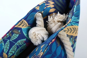Detail of blue canvas bag with leaf patterns and beige cotton rope handles with eyelets