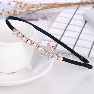 Close-up of black headband with rhinestone apple charm and pearl accents on white background