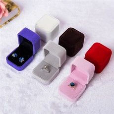 Overhead view of various colorful velvet jewelry boxes for rings and earrings on plush background