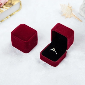 Detail view of red velvet ring boxes on faux fur background with a silver ring inside