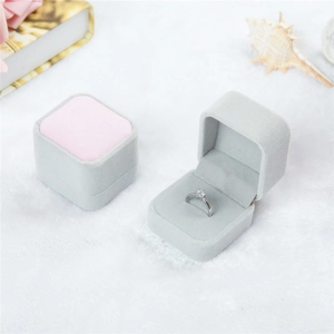 Close-up of a premium light gray and pink velvet ring box on a white textured background