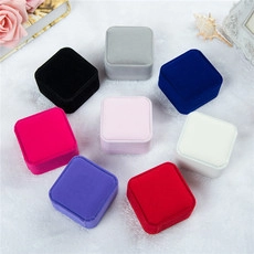 Top view of square velvet jewelry boxes in eight colors on white plush background