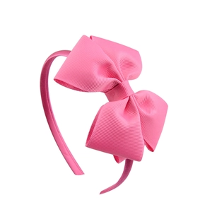 Detail of a pink headband featuring a large textured layered ribbon bow for children