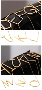 Detailed close-up of various large golden alphabet letter pendants on a slim chain necklace