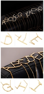 Detailed view of minimalist gold initial necklaces A to Q on black leather scroll