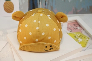 Detail of a ginger yellow baby baseball cap with white polka dots and cute animal ears