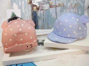 Detail of pink and blue baby baseball caps with polka dots and smiling face embroidery