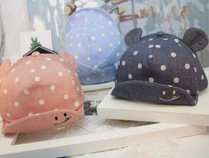 Detail of infant polka dot baseball caps with cute ears and smiling faces in pink and blue
