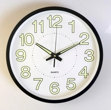 Detail of 14-inch silent clock with luminous green numbers on a black frame