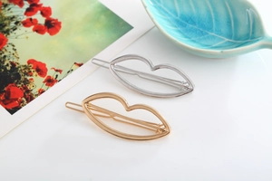 Close-up of minimalist hollow lip-shaped hair clips in polished gold and silver metal finishes