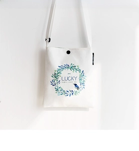 Detail of the white canvas crossbody bag with floral wreath and Lucky text design