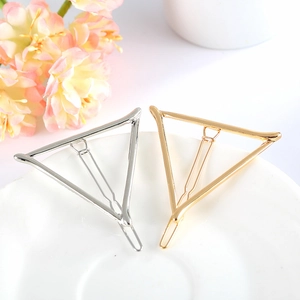 Detail of gold and silver geometric triangle metal hair clips with polished finish