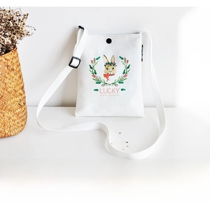 Close-up of white canvas crossbody bag with cute rabbit illustration and snap closure