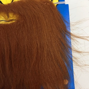 Macro shot of realistic reddish-brown synthetic mustache showing fiber texture