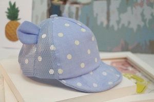 Detail of baby baseball cap in light blue with white polka dots and decorative ears