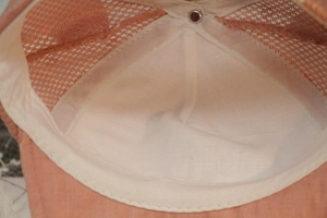 Detail of baby baseball cap interior showing orange mesh and soft beige sweatband