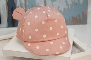 Detail view of pink baby baseball cap with white polka dots and cute ear decorations