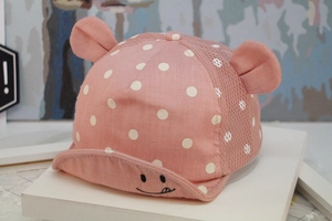 Close-up of pink baby baseball cap with white dots, mesh back and smiley face brim