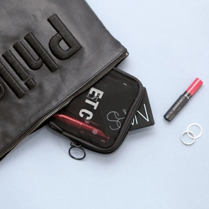 Black mesh makeup bag and leather clutch set with textured lettering for travel storage